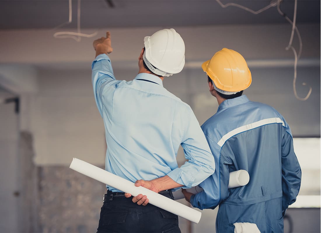 Insurance by Industry - Rear View of Two Contractors Holding Blueprints Looking at the Ceiling of a Newly Constructed Building Project
