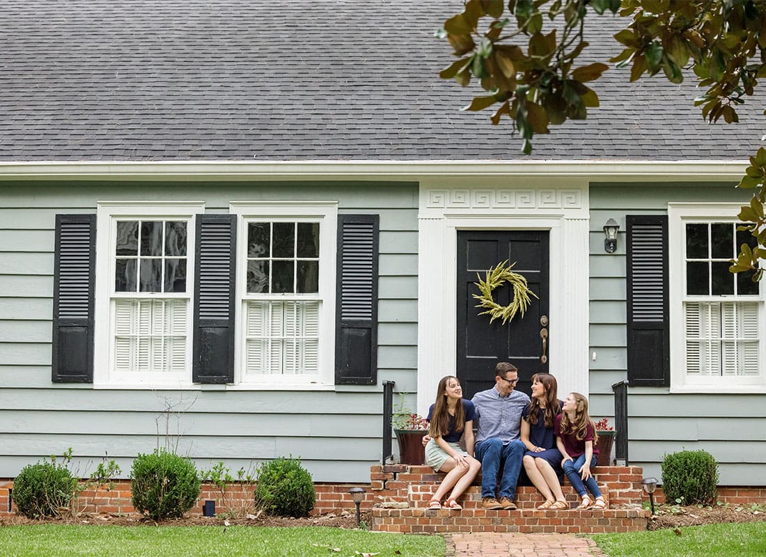 Personal Insurance - View of a Family with Two Children Sitting on the Front Steps of Their One Story Home